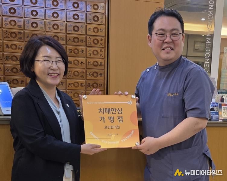 화성특례시가 22일 신규 치매안심가맹점으로 지정된 보건한의원에 현판을 전달하고 있다