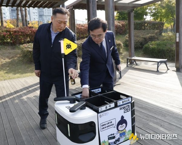 진교훈 서울 강서구청장(오른쪽)이 마곡하늬공원에서 열린 ‘AI 기반 자율주행 로봇서비스 실증 시연회’에서 빈 캔을 수거함에 넣고 있다.