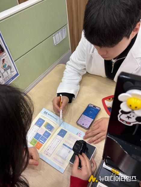 모바일 헬스케어사업 참여자가 모바일 앱(채움건강)과 활동량계(스마트밴드)에 대한 설명을 듣고 있다.