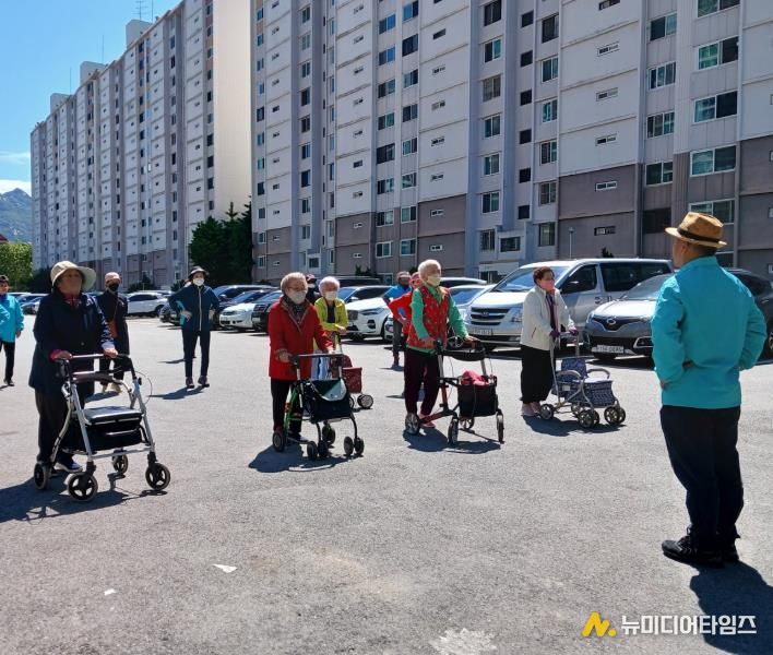 어르신들이 아파트 단지 앞에 모여 걷기 운동 시작 전 준비운동을 하고 있다