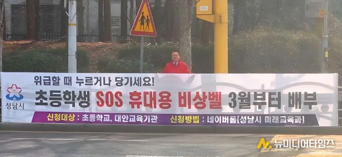황금석 성남시의원이 초등학교 인근에 설치된 ‘초등학생 SOS 휴대용 비상벨’ 신청 안내 현수막 앞에 서 있다