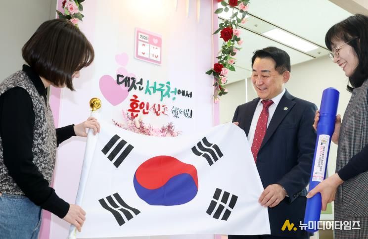 서철모 서구청장이 구청 민원실을 방문한 국제결혼 부부에게 태극기를 전하고 있다