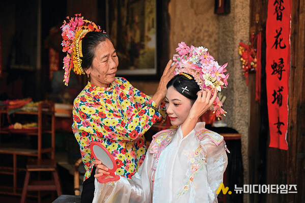 A tourist (right) is wearing flowery headwear at Xunpu Village of Quanzhou City, southeast China